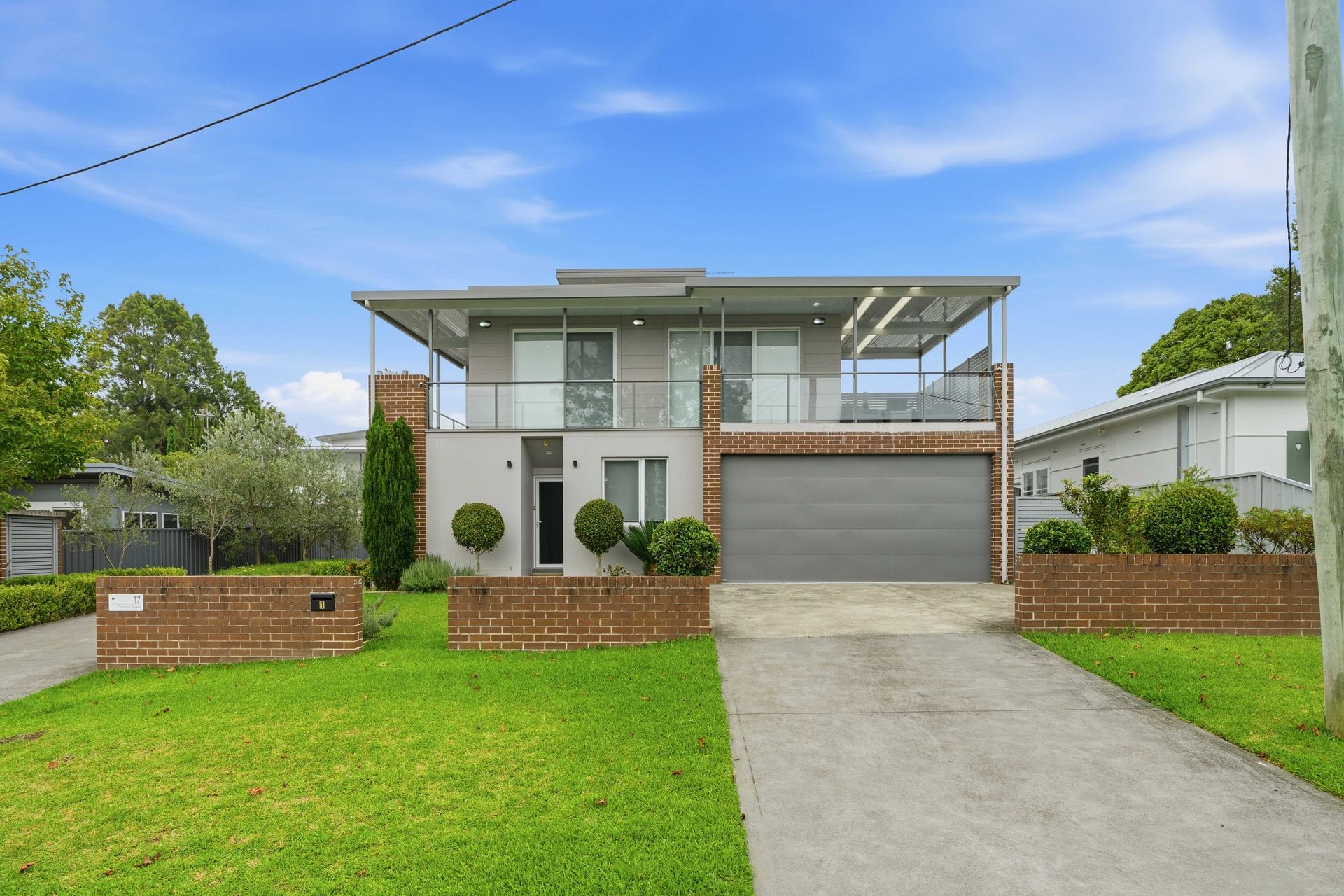Front exterior of the two-storey Bay View Beach House with lawn and driveway